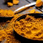 Close-up of vibrant turmeric powder with root on rustic wooden table, emphasizing texture and color., tags: von ein für strahlende - pexel